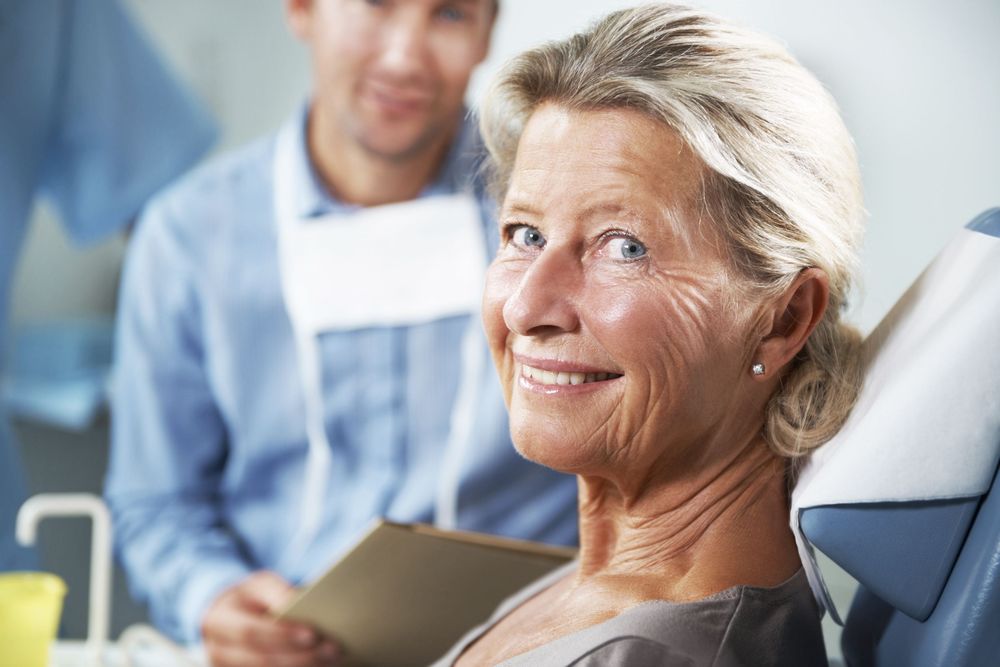An older woman smiles in the dental chair after full mouth reconstruction