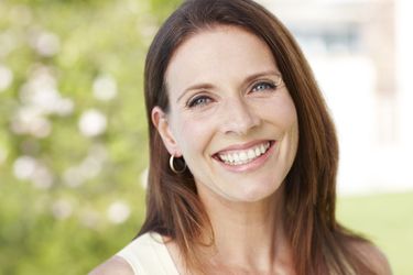 A middle-aged woman with a youthful face smiles at the camera