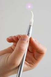 A photo of a hand holding a laser dental tool